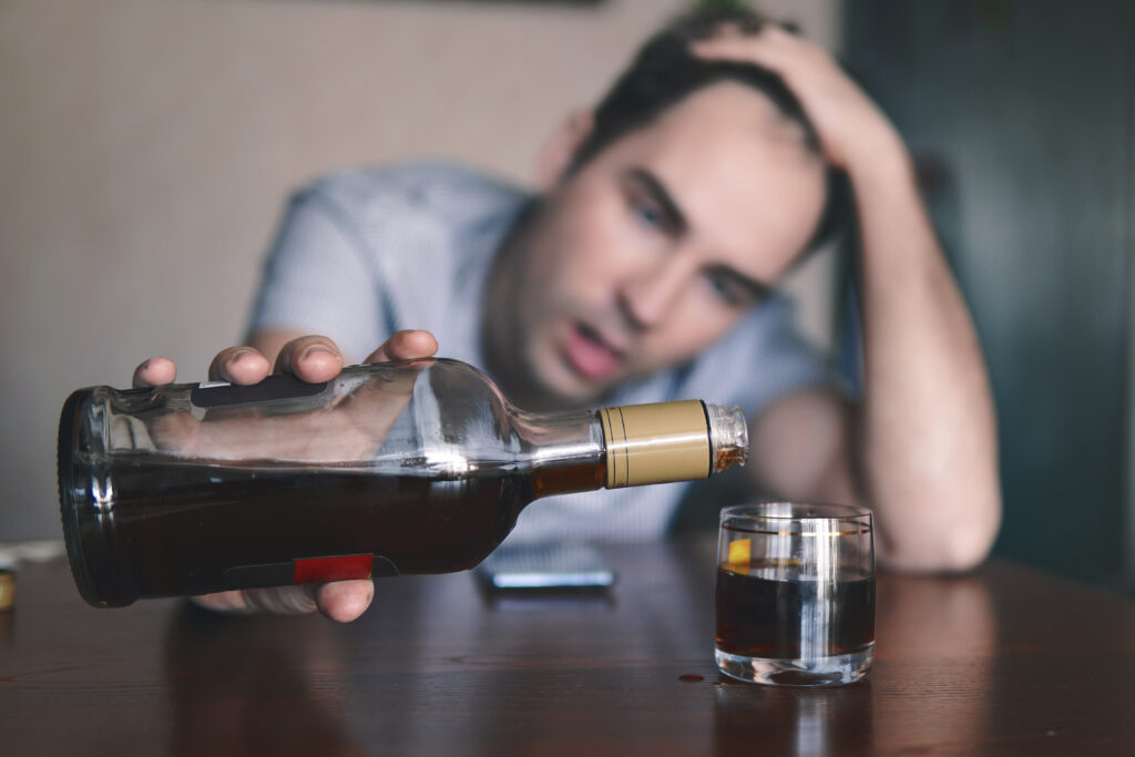 man die een glas alcohol inschenkt